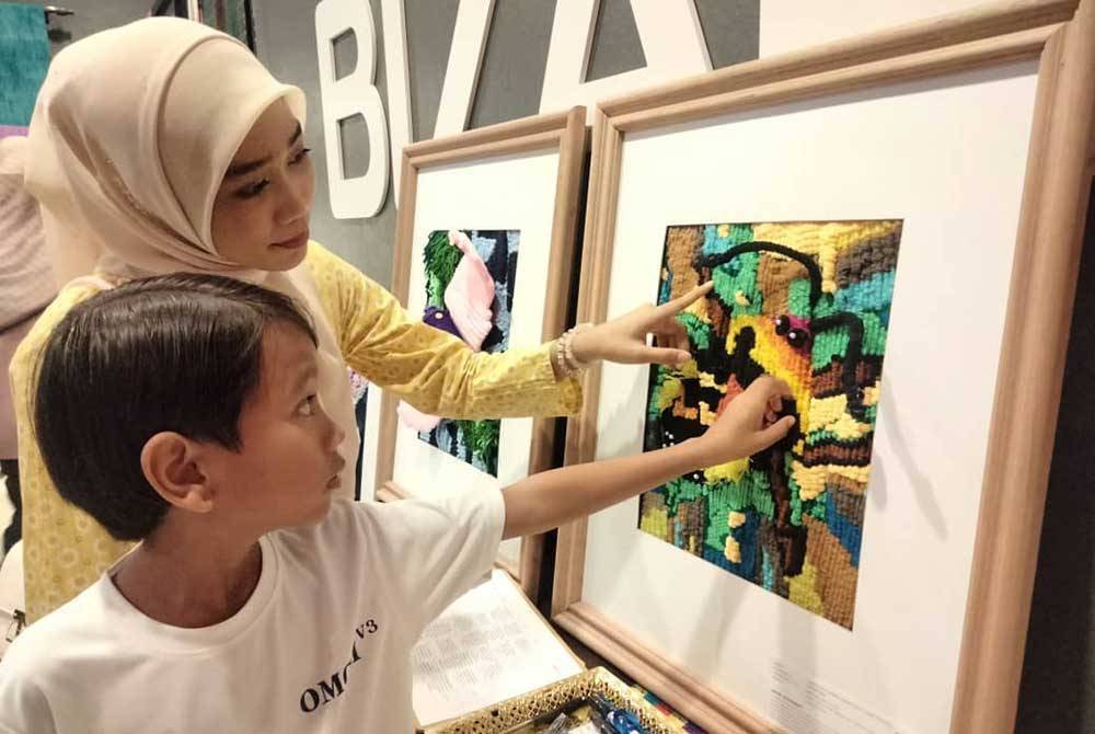 Tuan Nur Qistina Amani (kanan) dan Muhammad Nazmi melihat harlequin bug, hasil kolaboratif mereka.