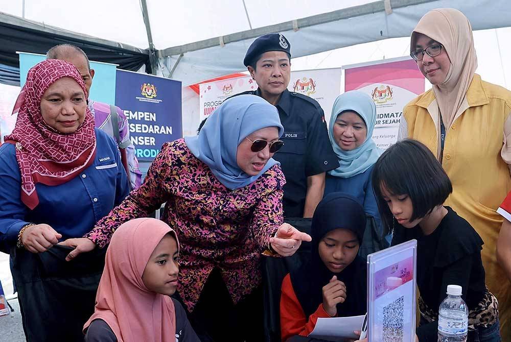 Nancy (tiga, kiri) melakukan lawatan di sekitar tapak pameran pada Program Komuniti Santuni Madani sempena Kembara Kasih KPWKM di Kampung Santubong pada Sabtu. Foto Bernama