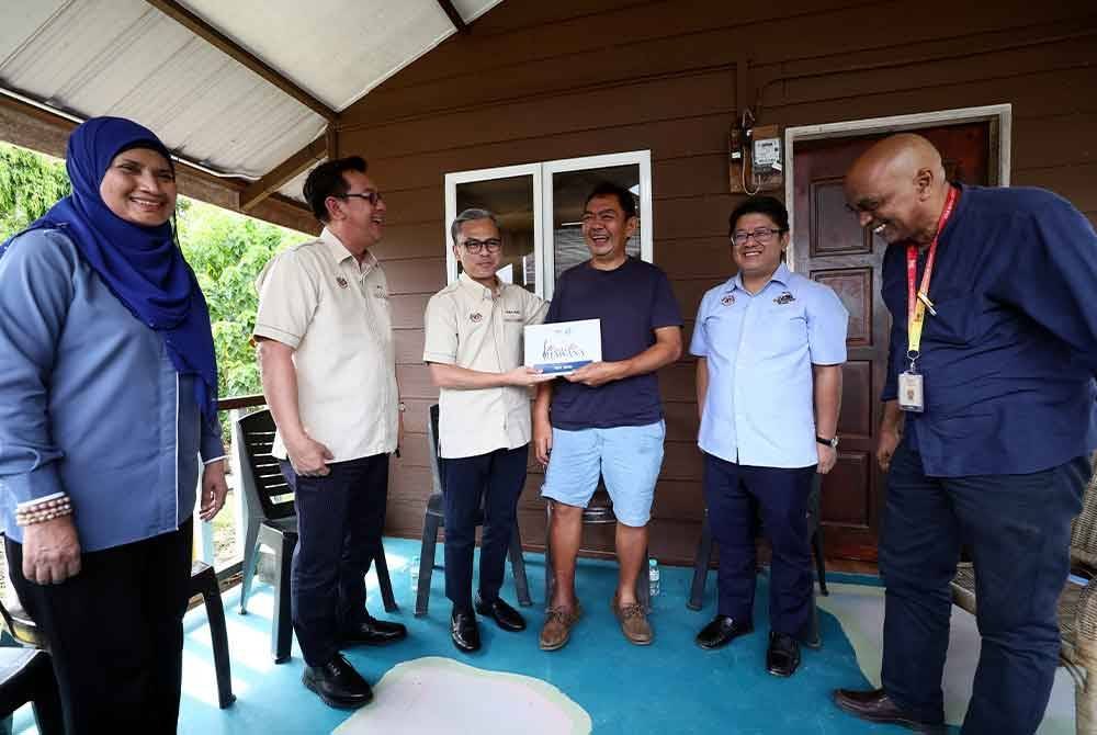 Ewon bersama Fahmi menyantuni editor sambilan New Straits Times, Roy Goh yang menghidap penyakit angin ahmar dan terjejas banjir di kediamannya di Kampung Dabak. Foto Bernama