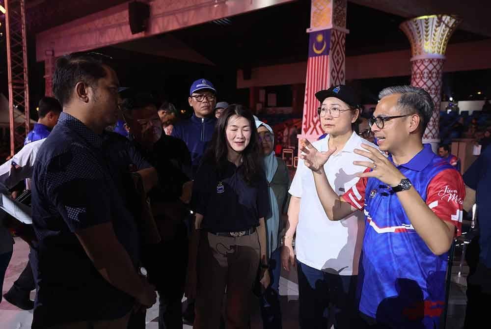 Fahmi (kanan) berkata sesuatu sewaktu menyaksikan raptai penuh sambutan Hari Malaysia di Padang Merdeka. Foto Bernama