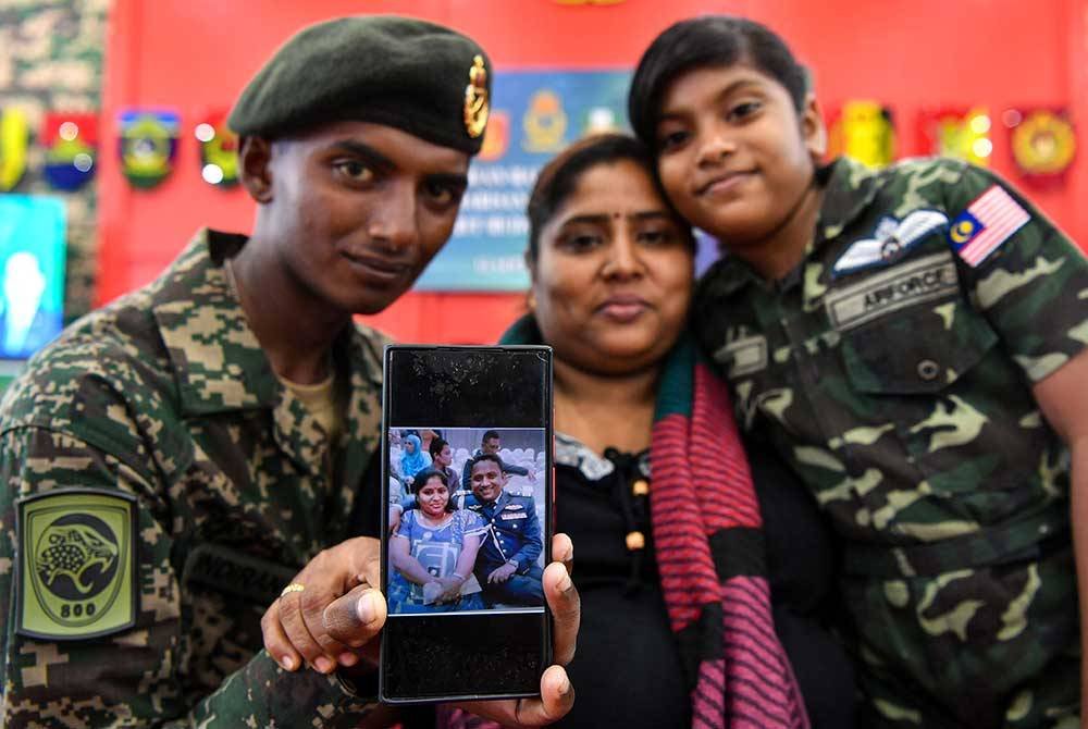 Indiran (kiri) bergambar bersama ibu Usha (tengah) dan adiknya Maitraashnni (kanan) sambil menunjukkan rakaman foto mendiang ayahnya Kayamboo pada majlis Perbarisan Tamat Perajurit Muda Lelaki Siri 200/24 di Pusat Latihan Asas Tentera Darat (PUSASDA), pada Ahad. Foto Bernama