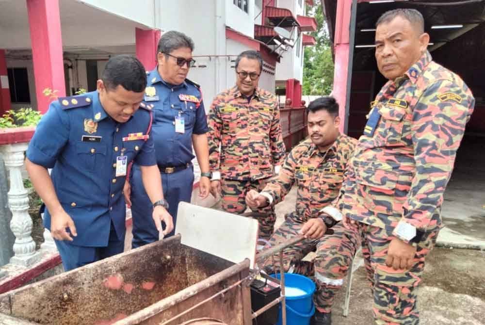 Mohd Azmi (kiri) dan ahli pasukan Rantau Mas menguji sistem pengesanan dan pemadaman kebakaran itu.