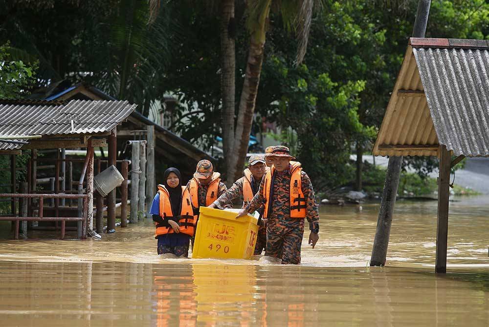 Anggota Pasukan Bomba dan Penyelamat Jitra menyelamatkan seorang mangsa banjir di Kampung Padang Luar. Foto Bernama