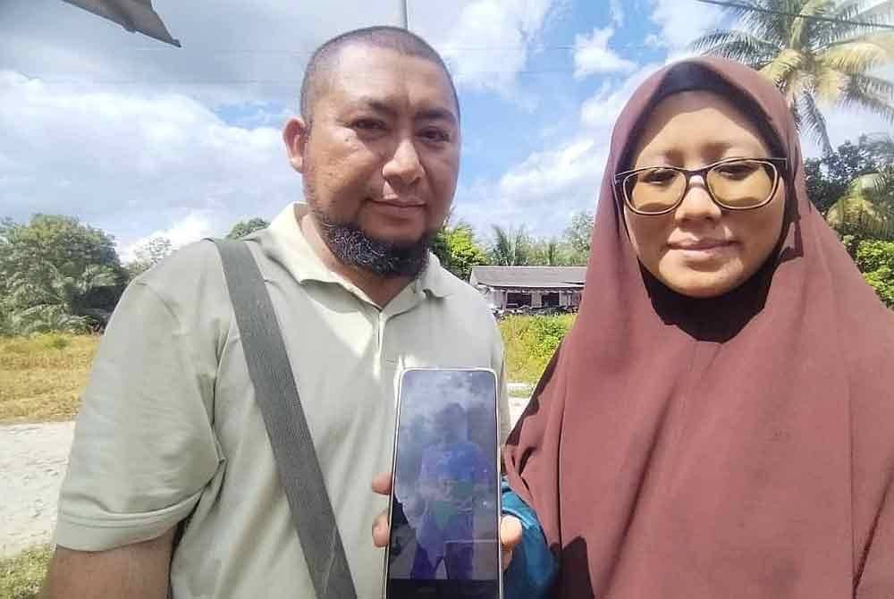 Nur Kamilah (kanan) bersama suami, Muhammad menunjukkan gambar anak mereka, Ibrahim yang hilang dan ditemukan lemas dalam parit di Taman Usrah dekat Kampung Renek, Besut pada malam Rabu.