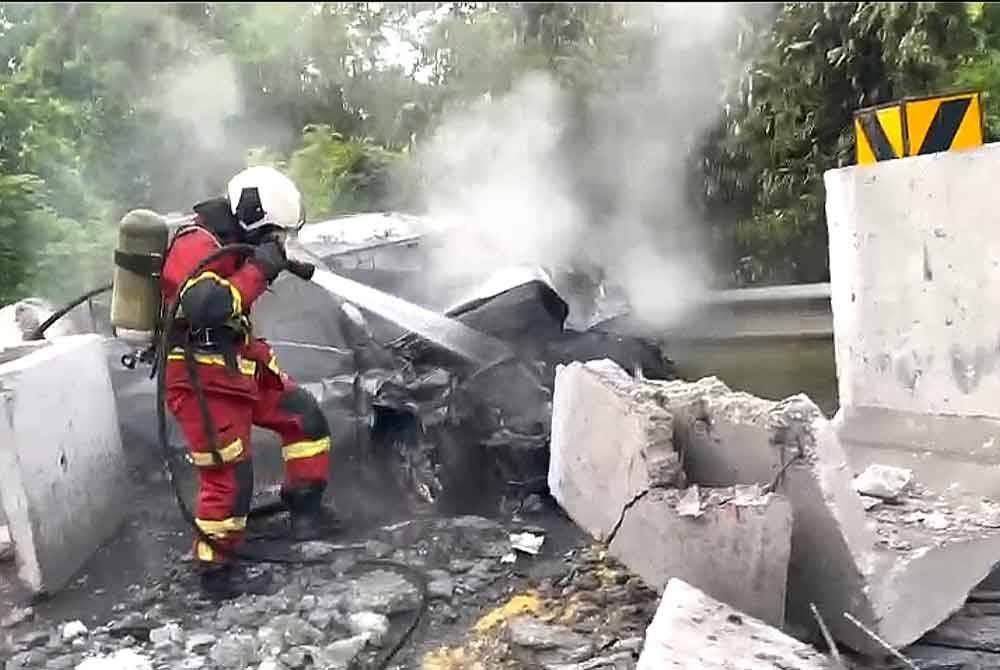 Anggota bomba memadamkan kebakaran melibatkan sebuah kereta yang melanggar bongkah konkrit yang jatuh dari sebuah treler dalam kejadian di Jalan Mambau-Seremban 2, Seremban pada Jumaat. Foto ihsan Bomba