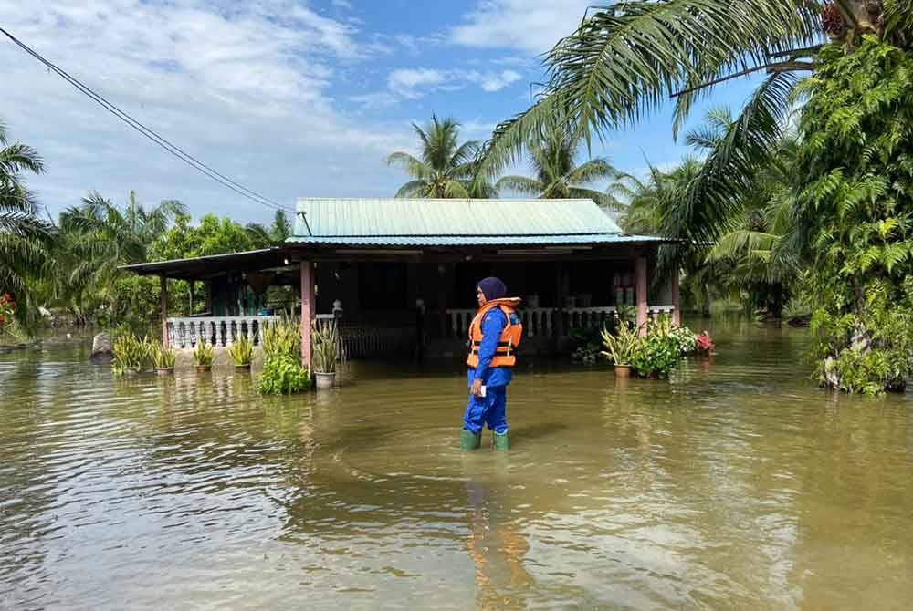 Anggota APM memantau rumah penduduk yang dinaiki air susulan fenomena air pasang besar yang berlaku di daerah Bagan Datuk.