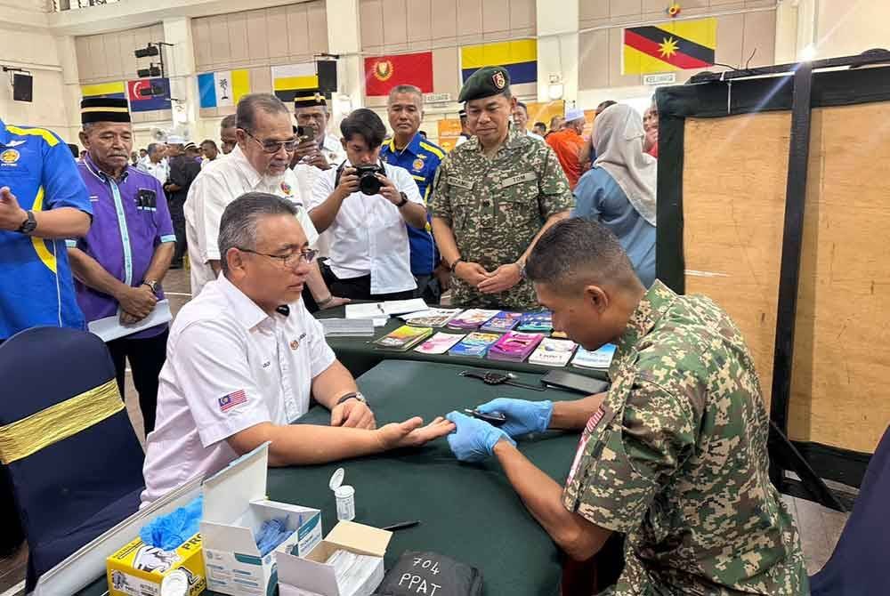 Adly (kiri) melakukan pemeriksaan kesihatan di kaunter yang dibuka pada Program Veteran Desa Madani di Rantau Panjang.