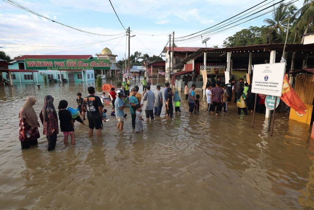 Orang ramai khususnya mereka yang terjejas banjir di sekitar Kampung Suka Menanti beratur bagi mengambil makanan percuma yang disediakan oleh salah seorang peniaga makanan di kampung itu. Foto Bernama