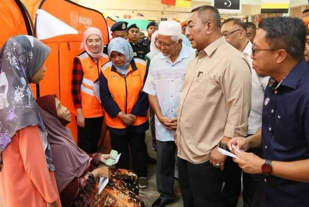 Muhammad Sanusi (dua dari kanan) berbual dengan mangsa banjir ditempatkan di PPS SMK Tanah Merah, di sini, pada Ahad. Foto: Urus Setia Penerangan Darul Aman (UPDA)