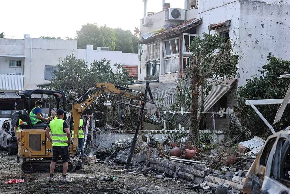 Sebuah jengkaut membersihkan sisa runtuhan di Kiryat Bialik di daerah Haifa yang dibedil Hizbullah. Foto AFP