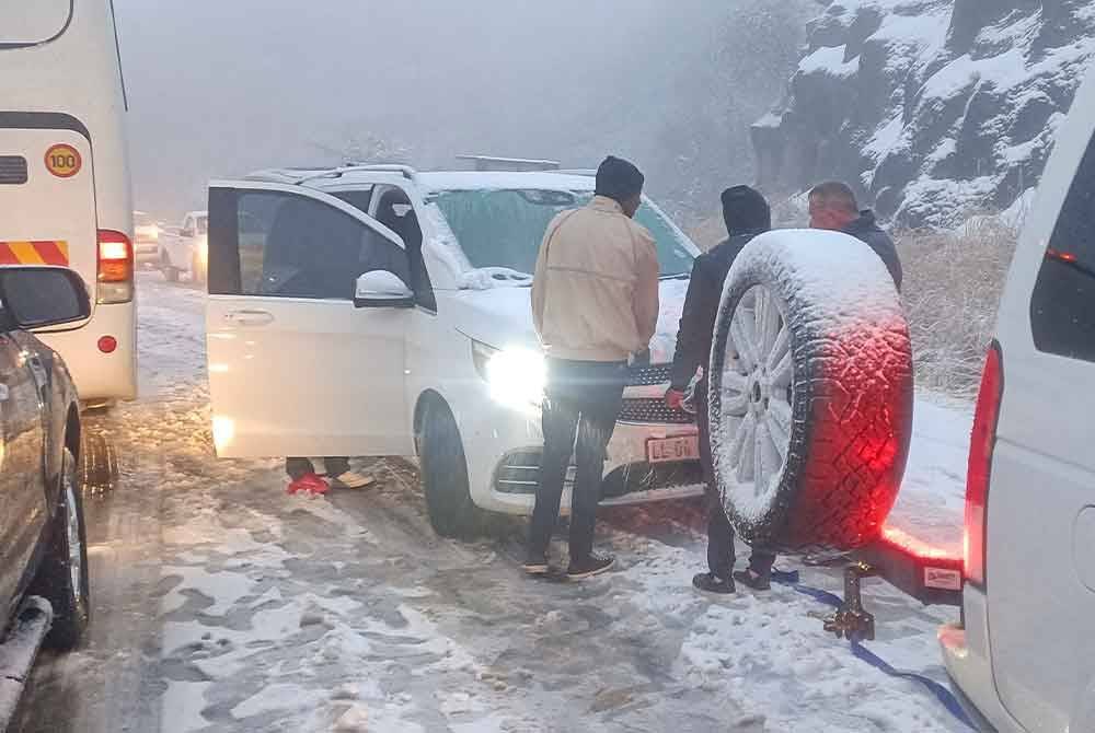 Beberapa pengguna lalu lintas membantu kereta yang terperangkap di dalam salji tebal di Oliviershoekpass berhampiran Harrismith. - Foto AFP