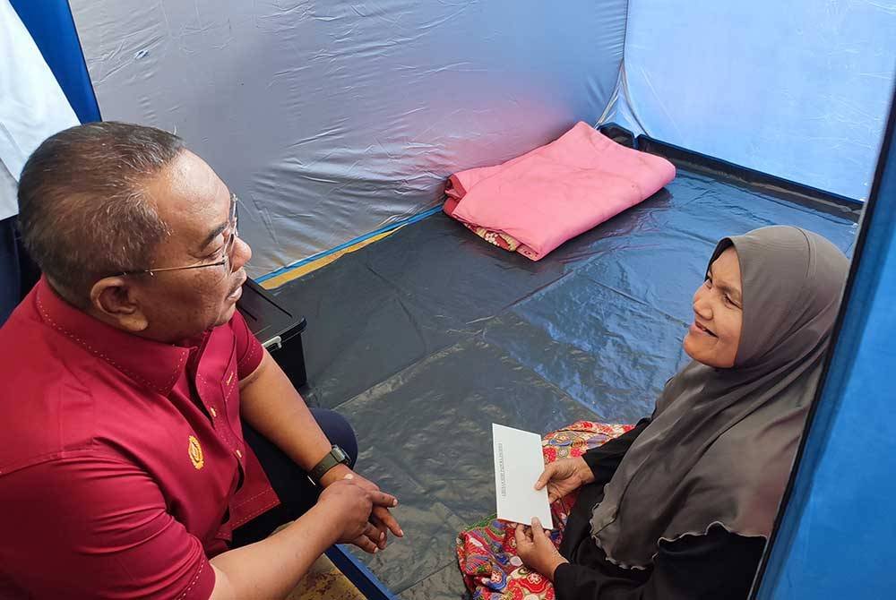 Muhammad Sanusi (kiri) melawat mangsa banjir, Nafisah Mohd Janan yang ditempatkan di PPS SMK Tuanku Seri Indera Putera pada Isnin.