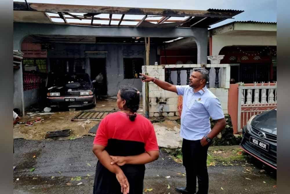 Arul Kumar meninjau kerosakan bumbung yang berlaku di rumah penduduk akibat diterbangkan angin kuat dalam kejadian petang Isnin.