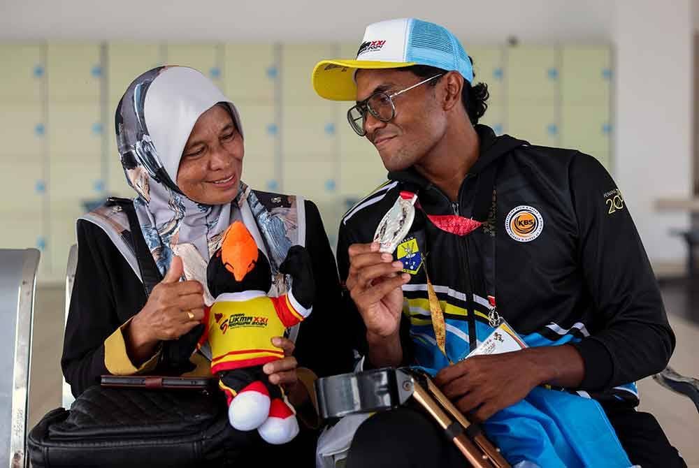 Perenang para Pulau Pinang Firdaus Fariduddin Noordin menunjukkan pingat perak yang dimenanginya dalam acara 50 meter gaya bebas S9 (kecacatan fizikal) kepada ibunya Jumabee Latiff, 64, pada temasya Para Sukma Sarawak 2024 di Pusat Akuatik Pandelela Rinong pada Selasa. Foto Bernama