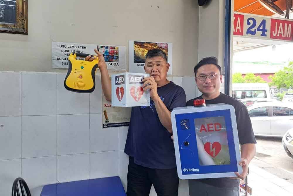 Chee Heng (kiri) dan E C Tan menunjukkan mesin defibrillator luaran automatik (AED) yang ditempatkan di sebuah restoran di Puchong Utama di sini.