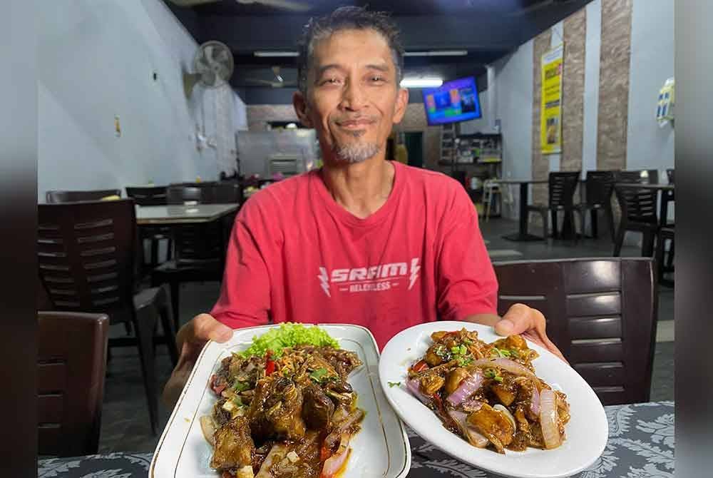 Pengasas Lagenda Nasi Ujang, Marzri Mat Khalil menunjukkan lauk kambing dan ayam bagi menu nasi ujang yang dijual