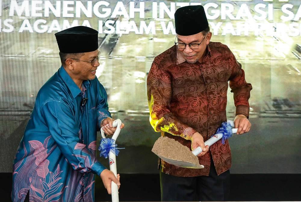 Anwar bersama Mohd Na’im Mokhtar (kiri) melakukan gimik pada Majlis Pecah Tanah Projek Pembinaan Sekolah Menengah Integrasi Sains Tahfiz (SMISTA) di Taman Alam Sutera, Bukit Jalil pada Khamis. Foto Bernama