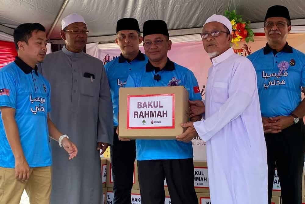 Mohd Na’im (tiga dari kanan) menyampaikan bakul makanan kepada penerima pada Majlis Perasmian Santuni Komuniti Madani di Masjid Saidina Umar Al-khattab Mukim Telekong di Kuala Krai pada Jumaat.