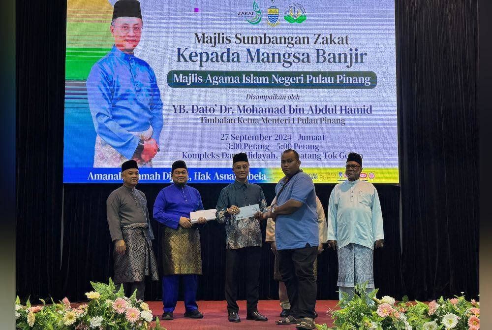 Mohamad (tiga dari kiri) menyampaikan bantuan wang tunai kepada salah seorang penerima Bantuan Agihan Khas Zakat MAINPP.