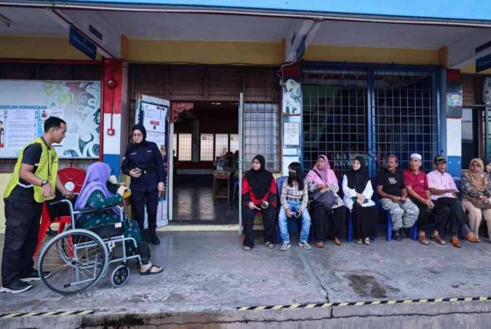 Antara pengundi yang menunggu giliran bagi menunaikan tanggungjawab mereka pada PRK DUN Mahkota di Pusat Mengundi Sekolah Kebangsaan Kampong Melayu hari ini. Foto Bernama