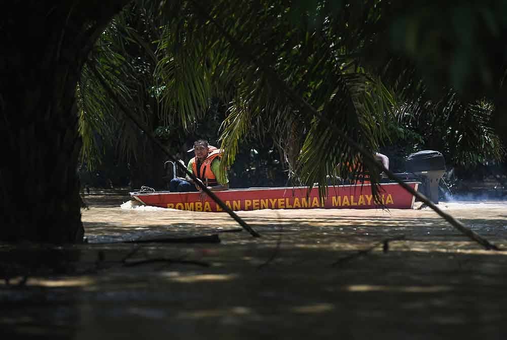 Anggota Bomba dan Penyelamat melakukan operasi mencari dan menyelamat dua beranak yang dihanyutkan arus deras banjir di Kampung Tanjung Kiri di sini, hari ini. Foto Bernama