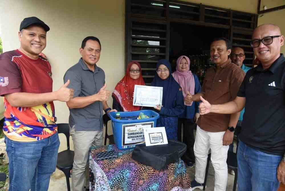 Fadzli (dua dari kiri) bergambar bersama Aisha Syafiyya (tengah) selepas menyampaikan sumbangan di kediaman keluarga Aisha Syafiyya