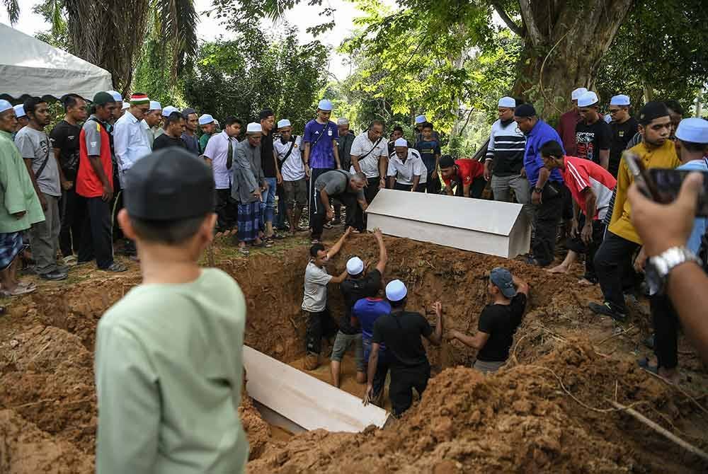 Jenazah Salmah Mat Zain, 46, dan anaknya, Muhammad Rosman Rohadi, 19, dikebumikan dalam satu liang lahad di Tanah Perkuburan Islam Masjid Aisyah Kampung Tanjung, di sini hari ini. Foto Bernama