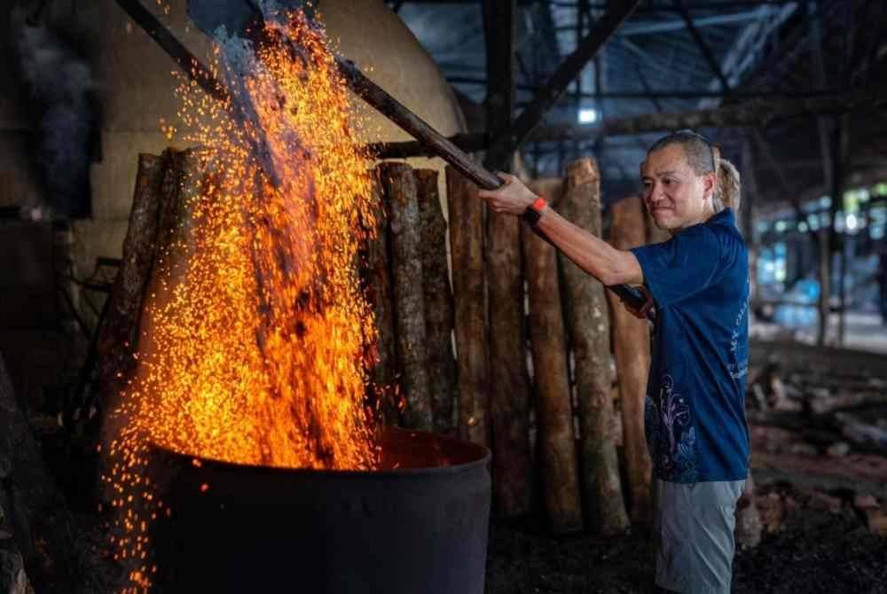 Kee Yong giat melakukan kerja-kerja memproses arang kayu bakau di kilang arang di Kuala Sepetang baru-baru ini. Foto Bernama