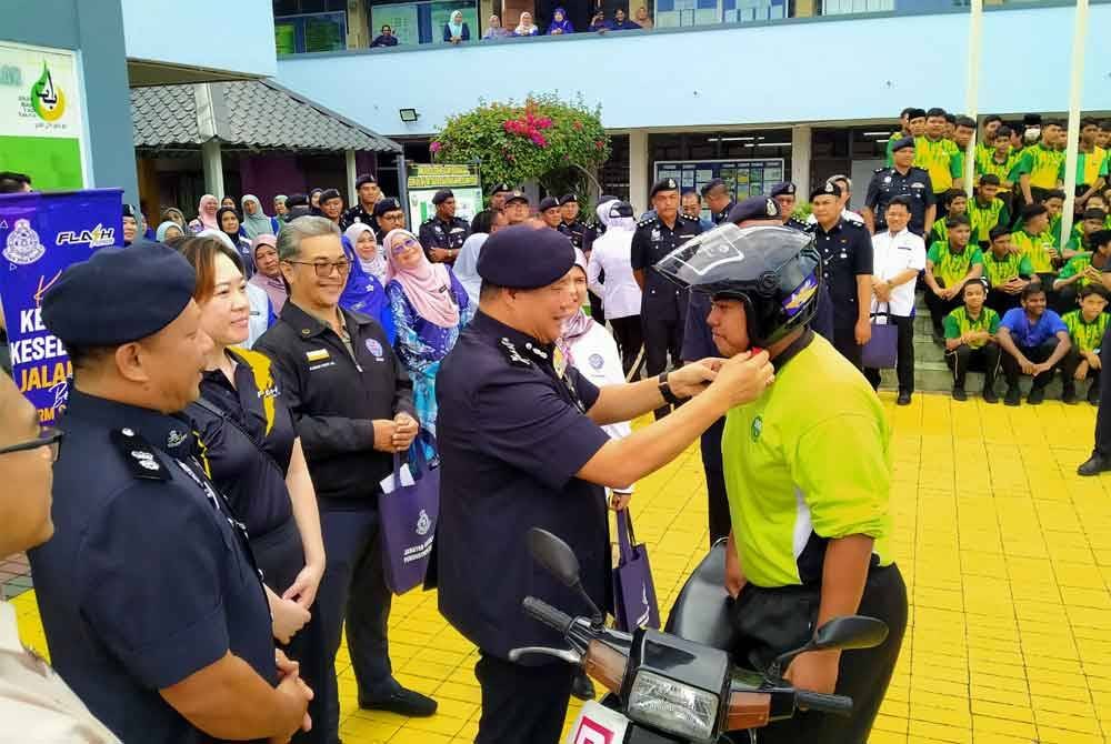 Azizi menyempurnakan gimik dengan memakaikan topi keledar kepada pelajar terpilih sempena Program Advokasi Kesedaran Keselamatan Jalan Raya Bersama PDRM dan Flash Express di SMK Dato&#039; Haji Mohd Taib, Chemor di sini pada Isnin.