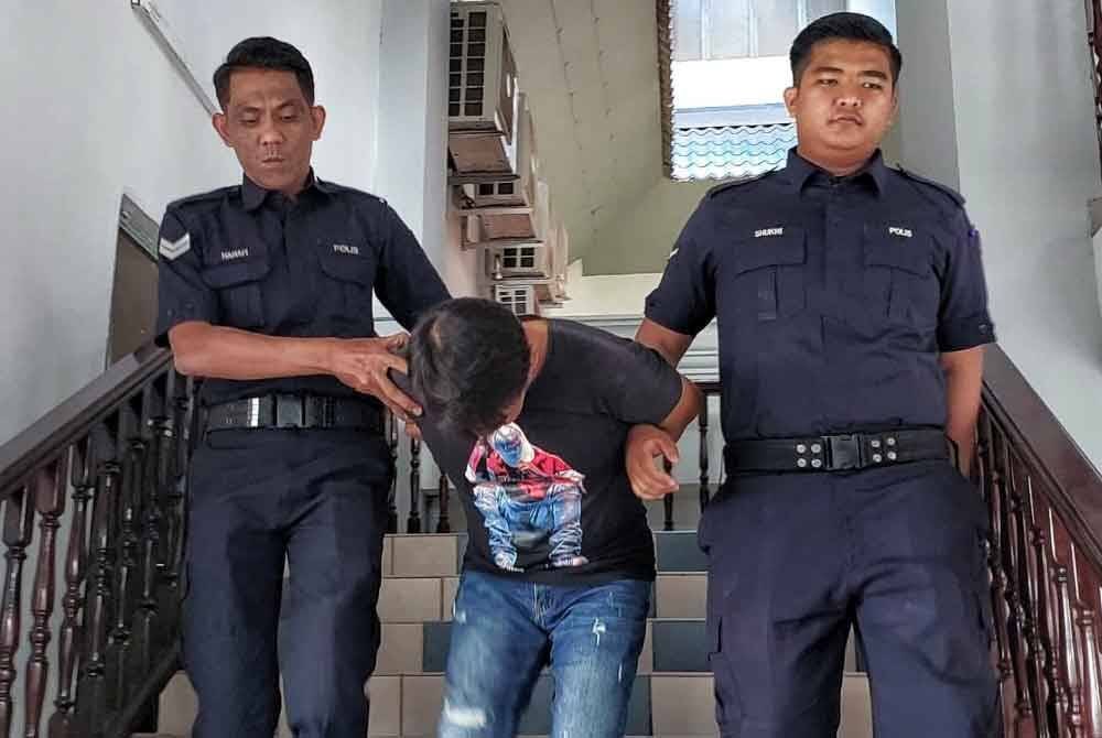 Setia (tengah) dibawa anggota polis keluar dari Mahkamah Majistret di Melaka, pada Isnin.