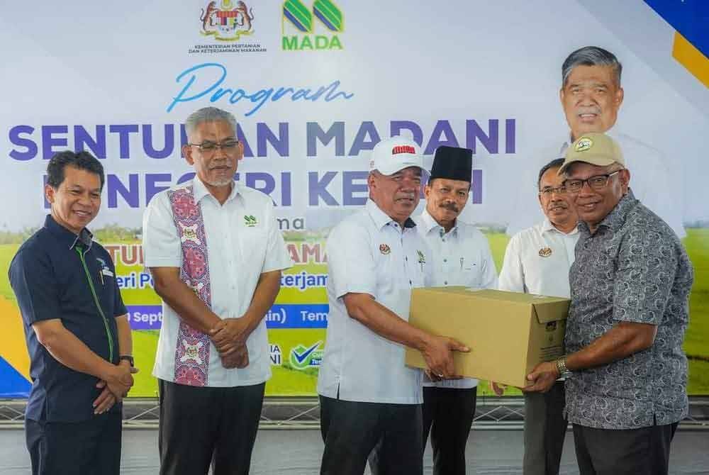 Mohamad (tiga kiri) menyerahkan simbolik bantuan awal Bakul Makanan Madani kepada wakil pesawah dan pengusaha pertanian di Pejabat Pertubuhan Peladang Kawasan MADA C-III Tajar, dekat sini.