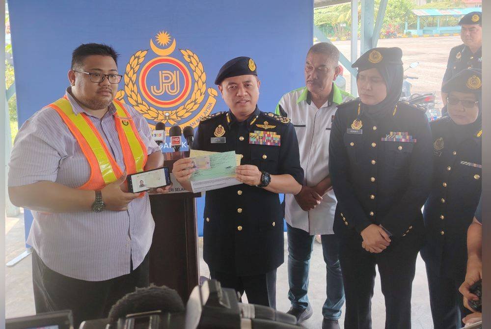 Aedy Fadly menunjukkan dokumen kelulusan Afifi (kiri) selepas menjadi individu pertama sertai Program Khas Peralihan LMM Kelas B2/B1 kepada LMM Kelas B di sebuah institut memandu di Kajang, pada Selasa.