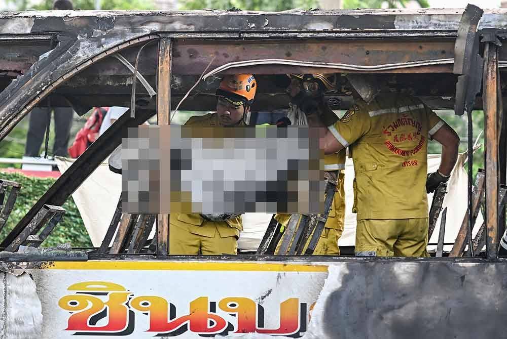 Seorang petugas penyelamat membawa mayat mangsa selepas bas membawa pelajar dan guru terbakar di pinggir Bangkok pada Selasa. Foto AFP