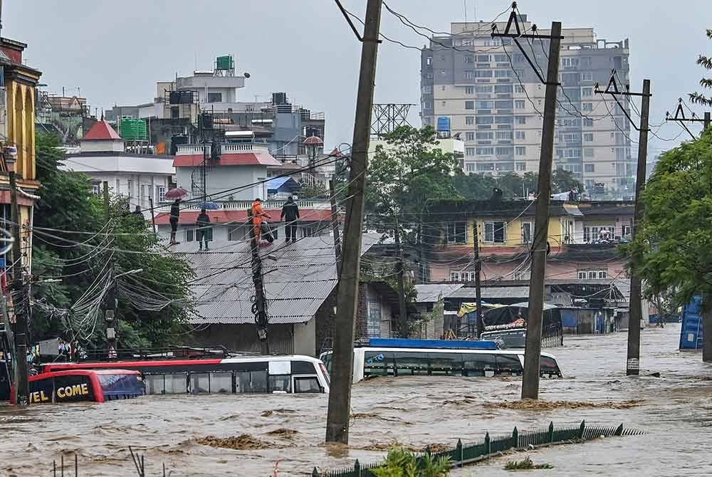 Penduduk memanjat bumbung ketika kawasan kejiranan mereka ditenggelami air banjir selepas Sungai Bagmati melimpah berikutan hujan monsun lebat di Kathmandu pada 28 September 2024. Foto AFP