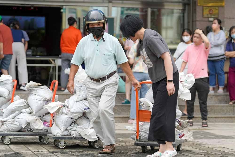 Orang ramai membawa beg pasir untuk digunakan menghalang air banjir memasuki penempatan di sekitar Kaohsiung. Foto AFP