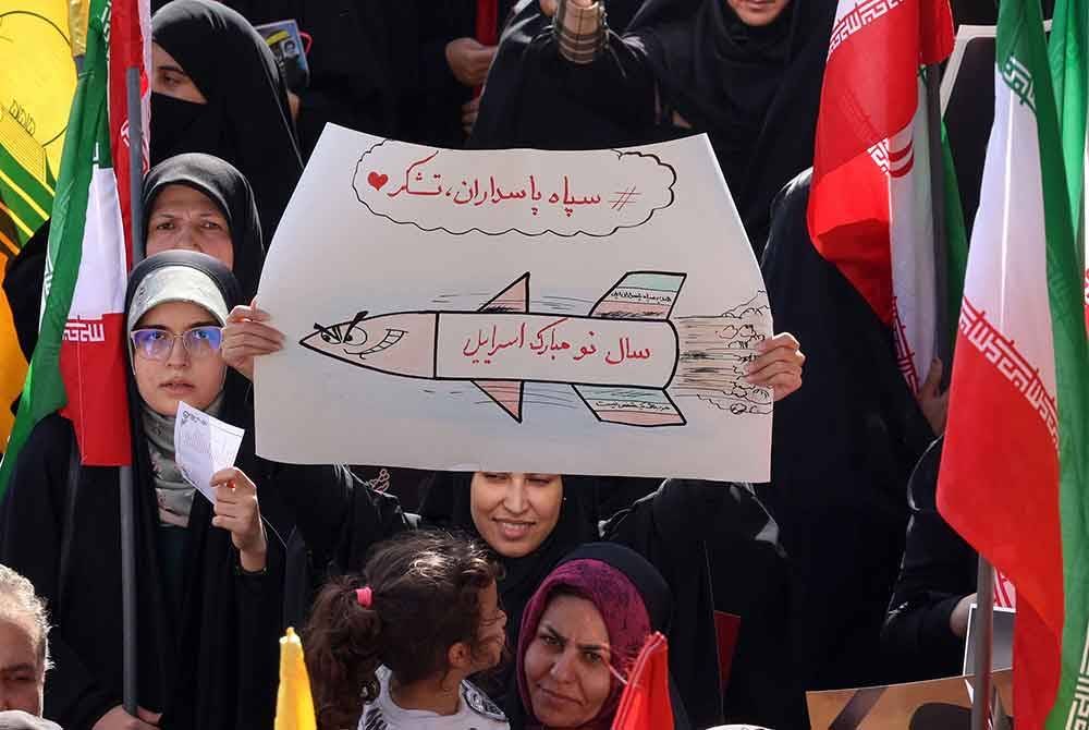 Penunjuk perasaan mengibarkan bendera Iran dan membawa lukisan peluru berpandu, semasa perhimpunan di Tehran pada 2 Oktober, sehari selepas Iran melepaskan peluru berpandu ke arah Israel.
Foto AFP