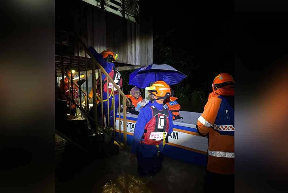 Anggota APM memindahkan mangsa terjejas banjir di Kampung Bukit Endoi, Parit Panjang, Baling. Foto APM