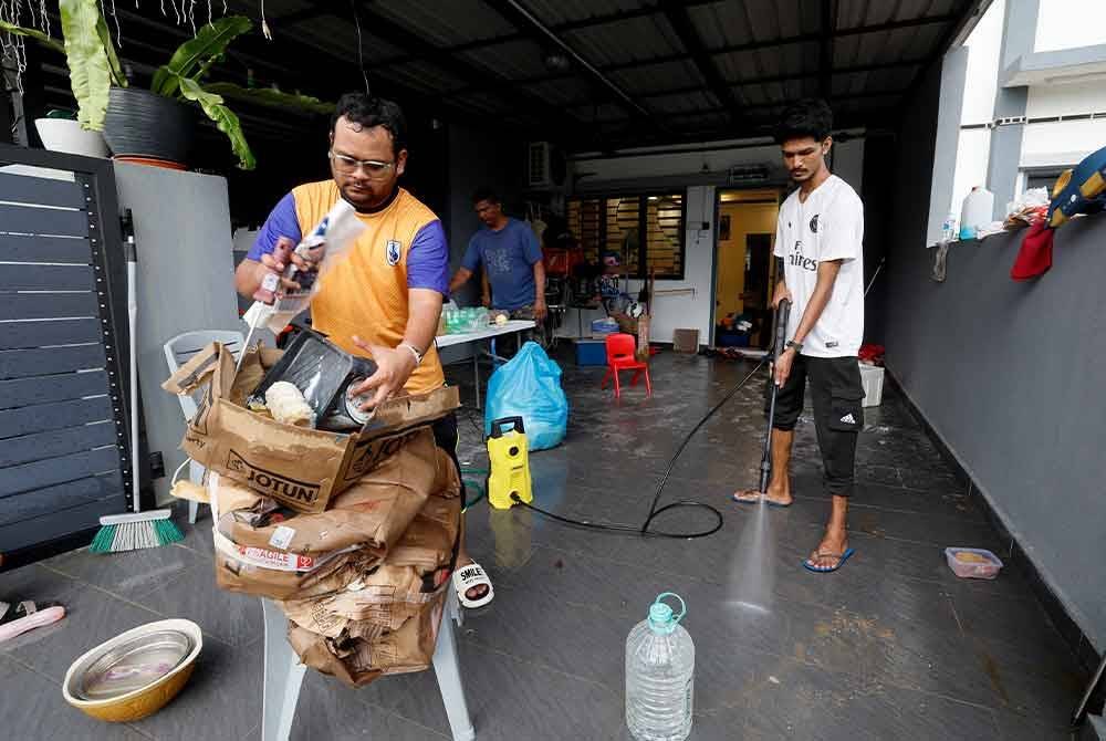 Mangsa banjir, Muhammad Salleh Majid, 33, (kiri) bersama ahli keluarganya bergotong-royong membersihkan rumah mereka selepas dilanda banjir kilat ketika tinjauan di Taman Saujana Aman, pada Jumaat. Foto Bernama