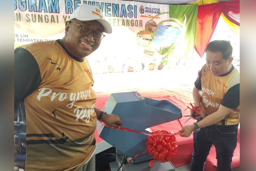 Suee Lim (kanan) sambil diiringi Pegawai Daerah Kuala Selangor, Mohd Raiz Radzuan memotong riben sebagai simbolik Program Rejuvenasi di Kampung Bagan Sungai Yu di sini pada Sabtu.