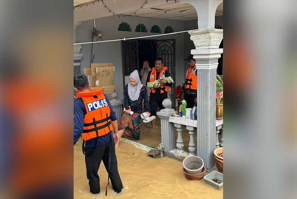 Anggota polis membantu memindahkan ibu dan anaknya yang terperangkap akibat banjir di Kampung Parit Jepun, Ulu Benut Simpang Renggam, Kluang. Foto IPD Kluang