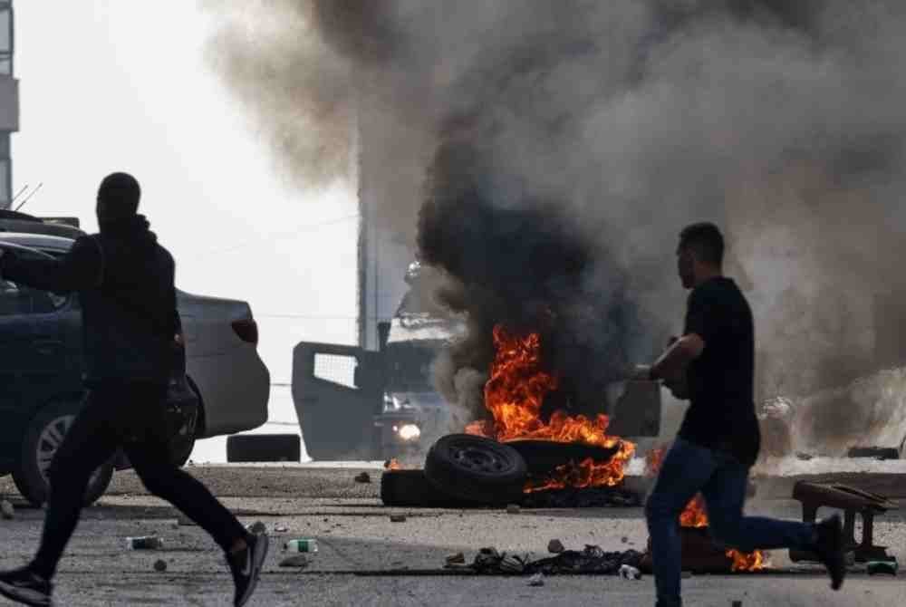 Penduduk Palestin berlari melepasi tayar yang terbakar ketika tentera Israel dikerahkan semasa serbuan tentera di Kafr Aqab timur Ramallah di Tebing Barat yang diduduki. Foto AFP