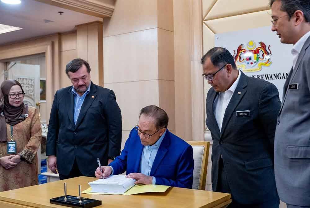 Anwar menandatangani dokumen rasmi belanjawan itu di Kementerian Kewangan hari ini. Foto Facebook Anwar Ibrahim