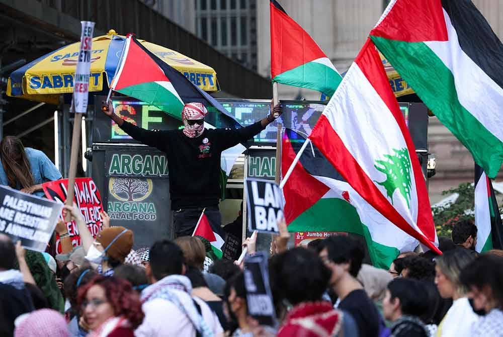 Penunjuk perasaan mengibarkan bendera Palestin dan Lubnan semasa perarakan menyokong Palestin di New York City sempena setahun serangan Israel ke atas Palestin. Foto AFP