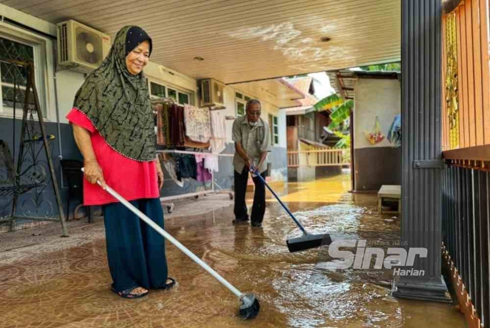 Mazni dan suaminya, Abdul Razak membersihkan rumah mereka di Kampung Alor Madi pada Selasa.