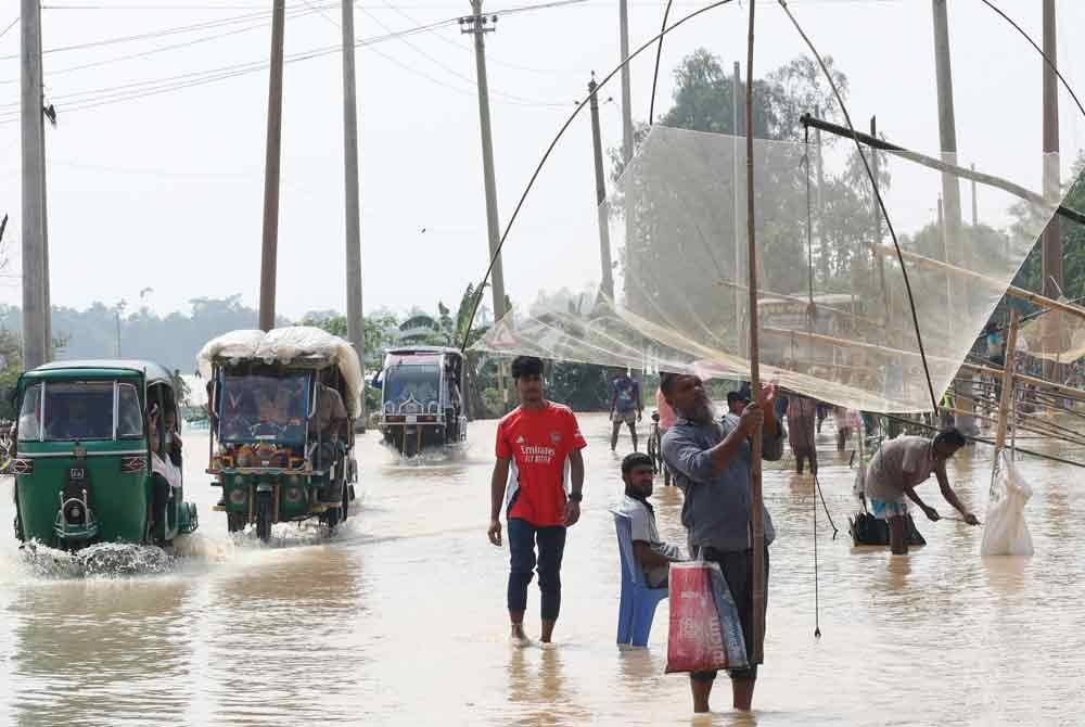 Orang ramai mengharungi banjir di Mymensingh, Bangladesh - Foto: Xinhua