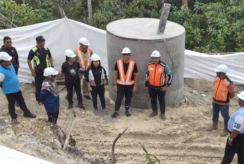 Izham (tengah) meninjau kerja pemasangan menara talian TNB di Sungai Chiling pada Selasa.