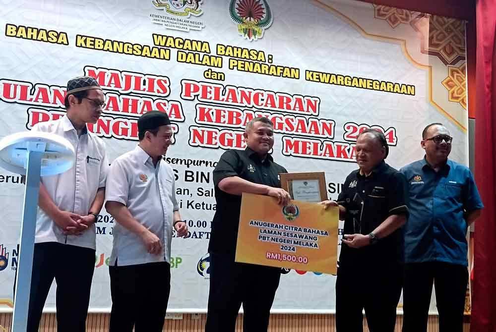 Rais Yasin (tengah) menyampaikan hadiah kepada pemenang Anugerah Citra Bahasa Laman Sesawang PBT Melaka pada perasmian dan Pelancaran Bulan Bahasa Kebangsaan peringkat negeri di Ayer Keroh hari ini. - Foto: Bernama