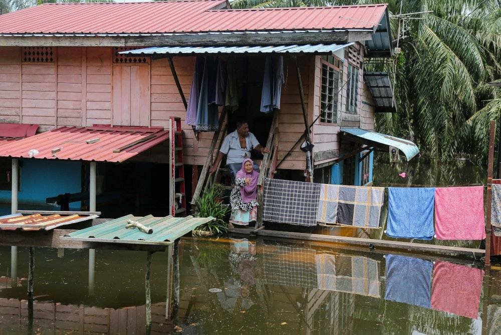 Pasangan suami isteri, Zaini Na'am, 76, dan isterinya, Halimah Mat Som, 71, duduk di tangga halaman rumah mereka di Kampung Beriah, Bagan Serai yang digenangi banjir termenung. Foto Bernama