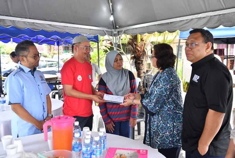 Azlinda (dua, kanan) menyampaikan sumbangan kepada bapa Allahyarham Ku Adib.