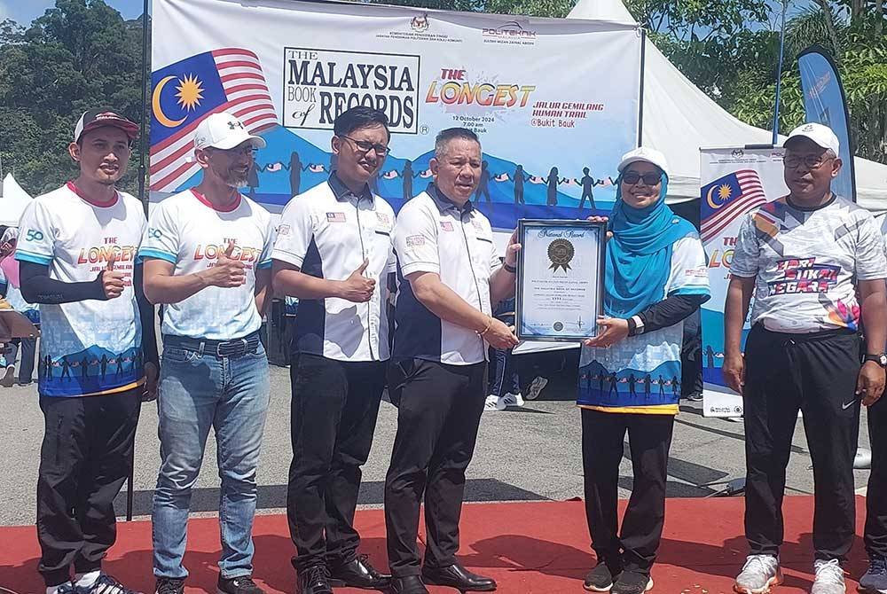 Edwin (empat dari kiri) menyerahkan sijil MBOR kepada Zamra (dua dari kanan) pada Majlis Perasmian The Longest Jalur Gemilang Human Trail @ Bukit Bauk di Taman Rekreasi Bukit Bauk pada Sabtu.